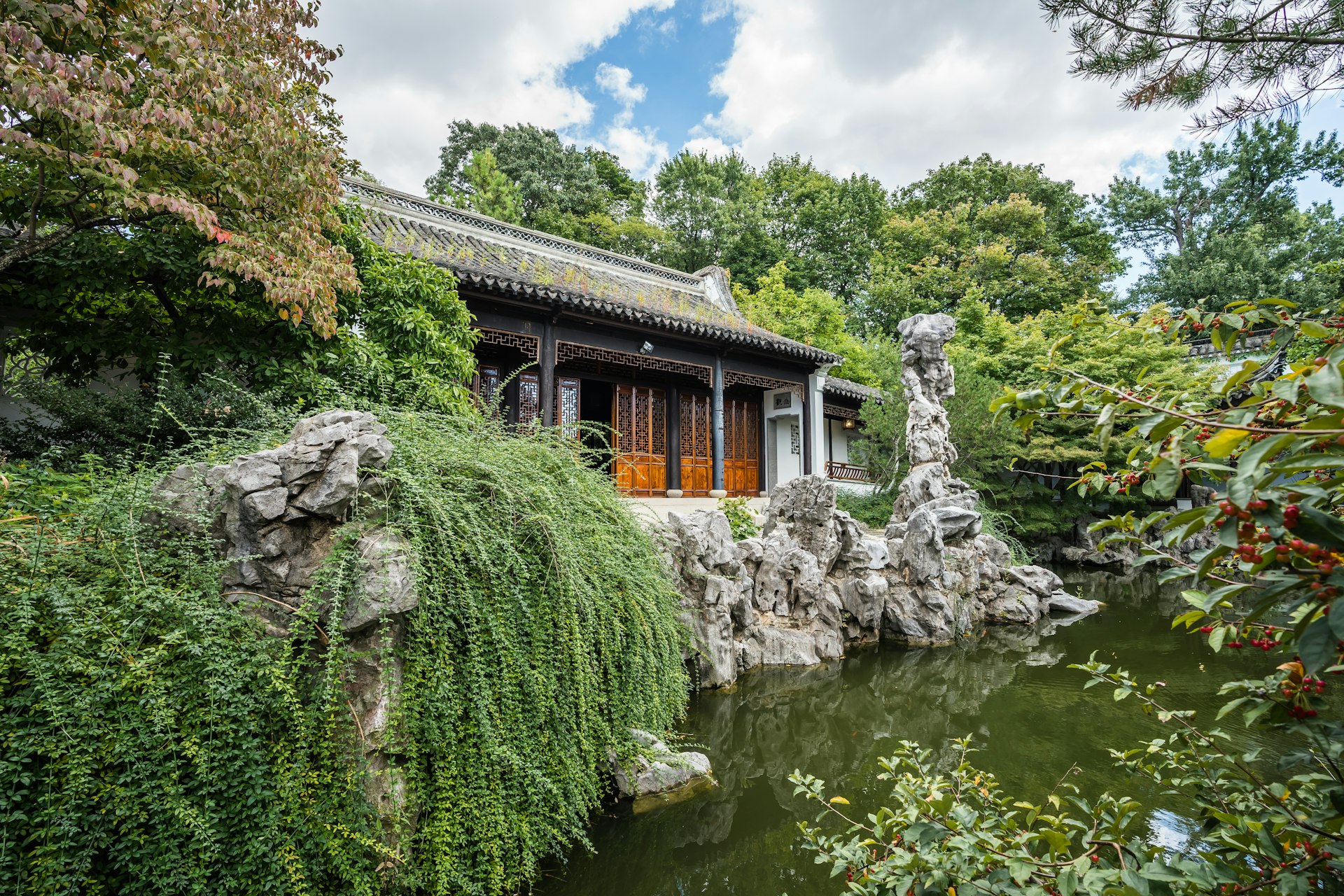 A pagoda-style roofed pavilion on a pond in the Chinese Scholar's Garden, surrounded by green trees