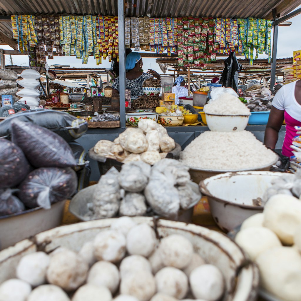 Woman at a market stall selling food such as Fufu, rice, beans, groundnuts and Cassave powder.