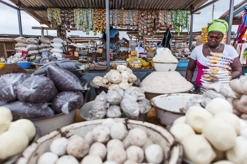 Woman at a market stall selling food such as Fufu, rice, beans, groundnuts and Cassave powder.