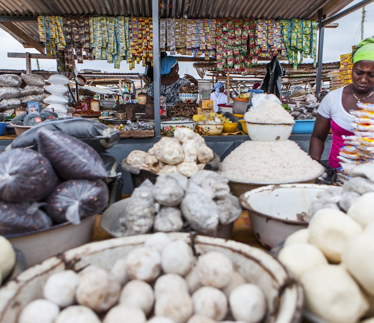 Woman at a market stall selling food such as Fufu, rice, beans, groundnuts and Cassave powder.