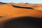 Couple walking along edge of sand dunes,Soussvlei,Namibia