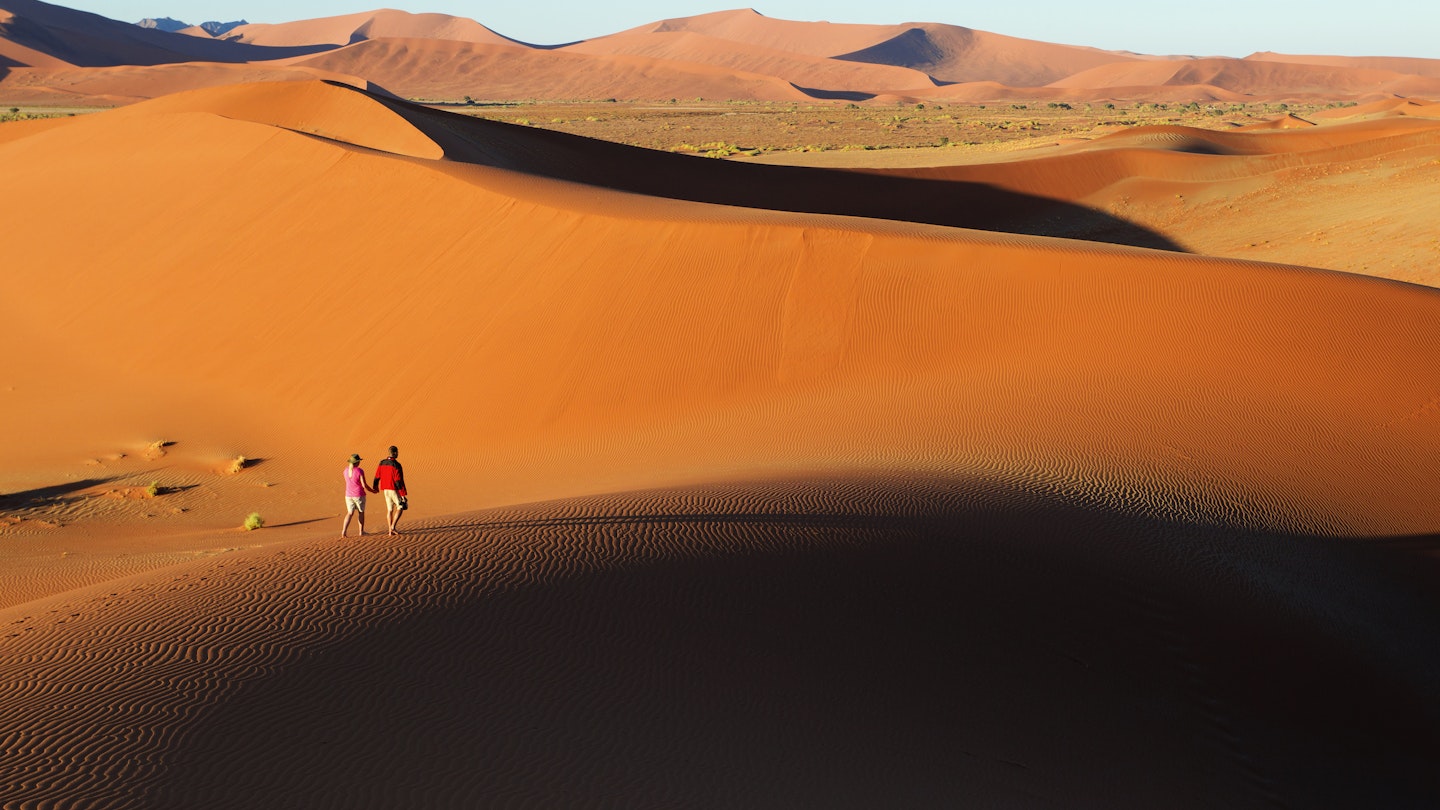 Couple walking along edge of sand dunes,Soussvlei,Namibia