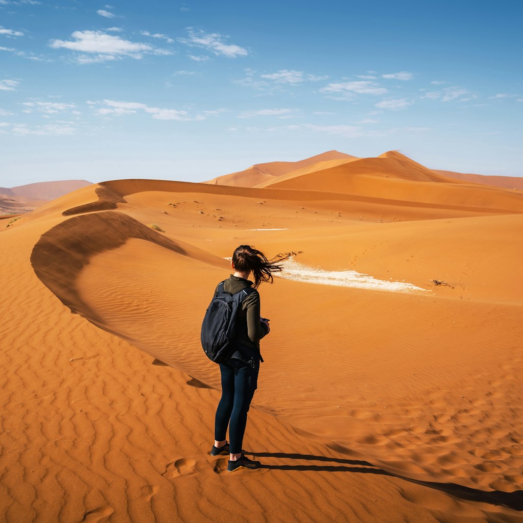Active female traveler hiking on the dunes around Deadvlei in the Namib Desert, Namib-Naukluft National Park, Namibia, Africa.