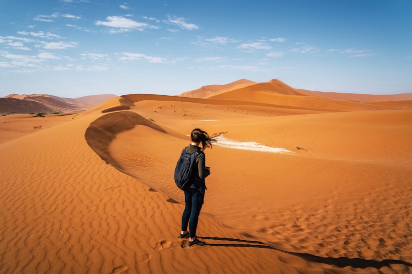 Active female traveler hiking on the dunes around Deadvlei in the Namib Desert, Namib-Naukluft National Park, Namibia, Africa.