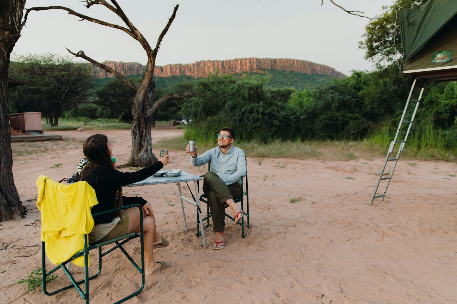 Two travelers raise a toast at their campsite in Namibia