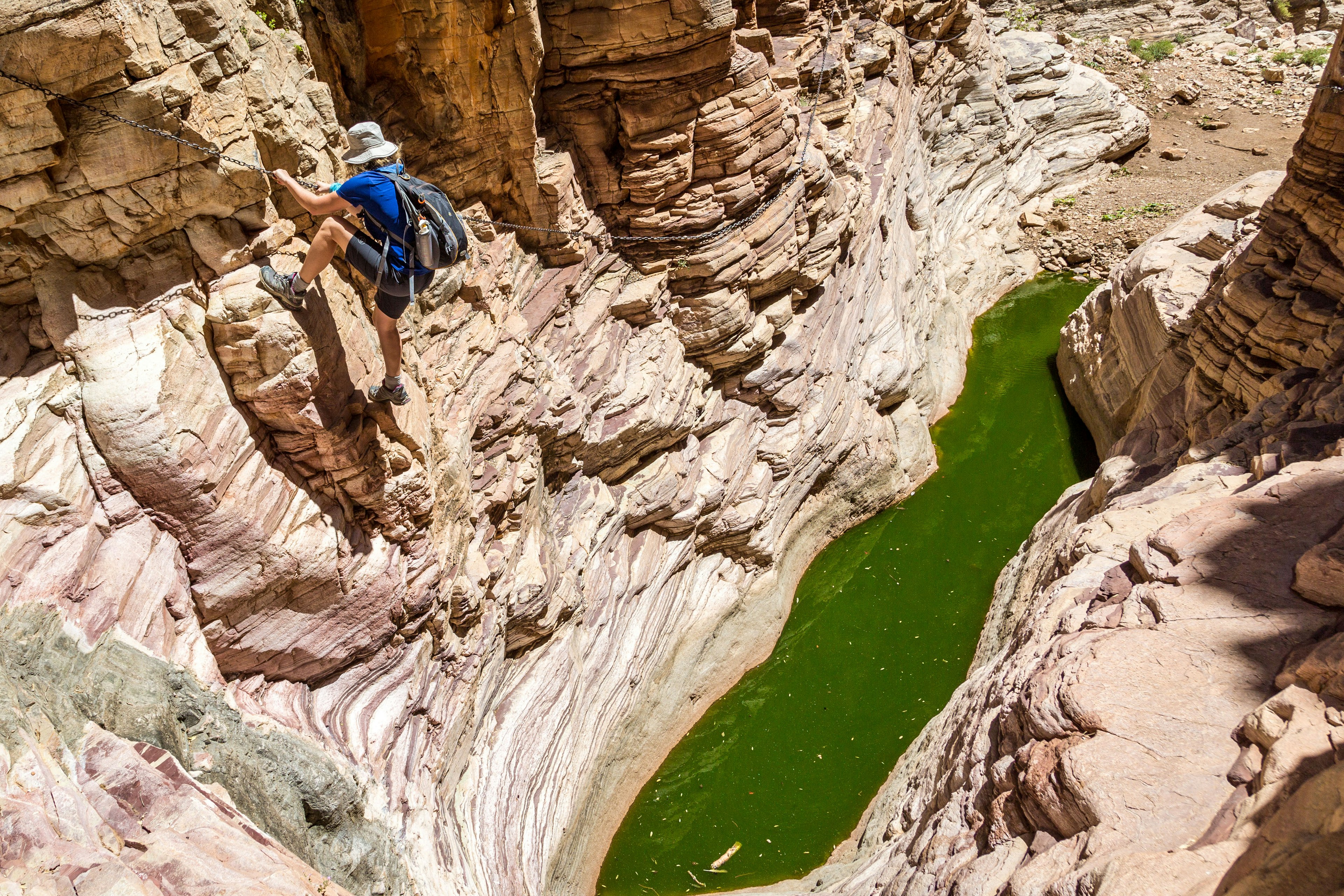 Young woman climbing in a canyon above a natural pool, Olive Trail, Namibia