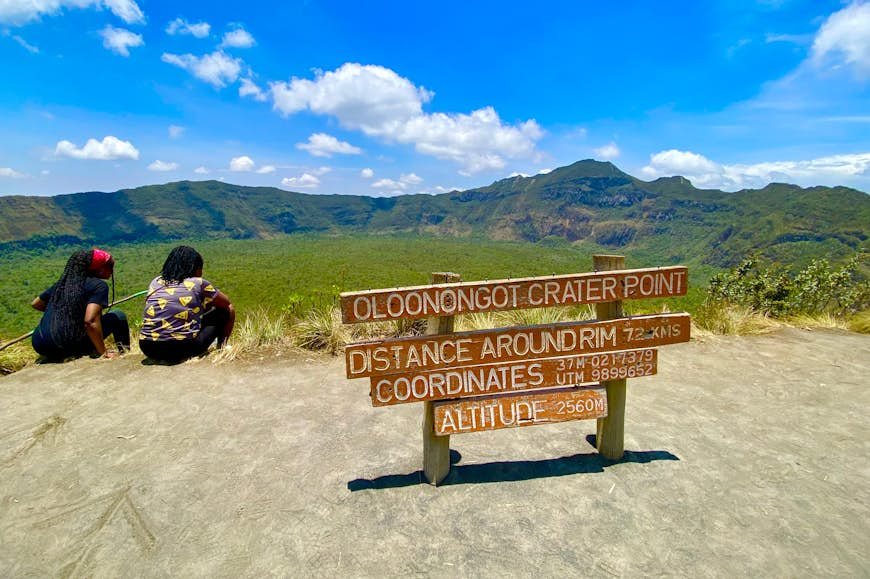 Two hikers sit facing a volcanic peak in a national park