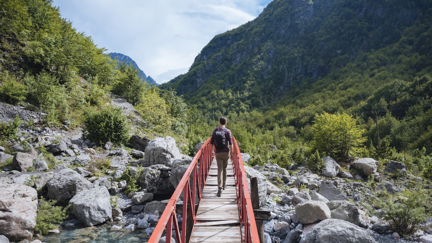 Rear view of man crossing bridge, Accursed mountains, Theth, Shkoder, Albania, Europe