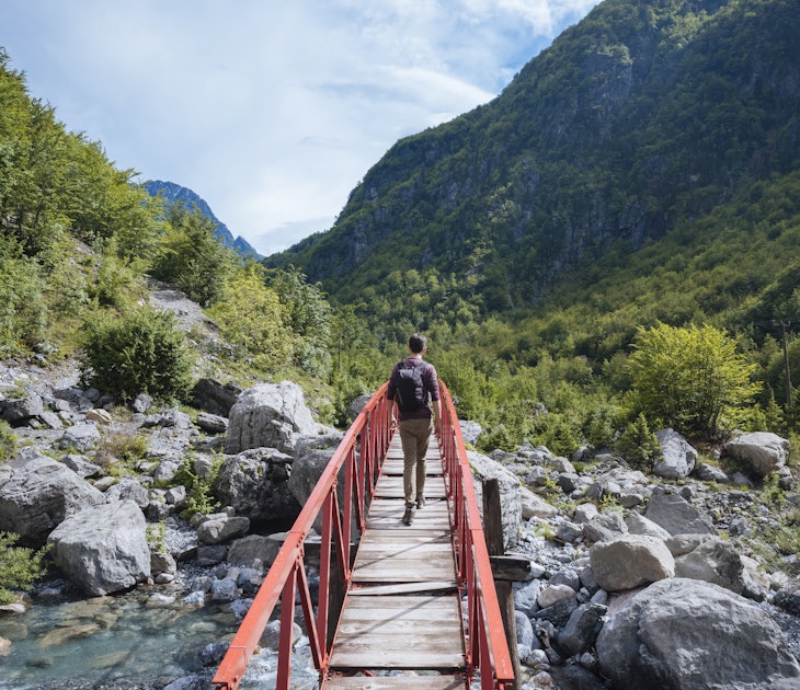Rear view of man crossing bridge, Accursed mountains, Theth, Shkoder, Albania, Europe
