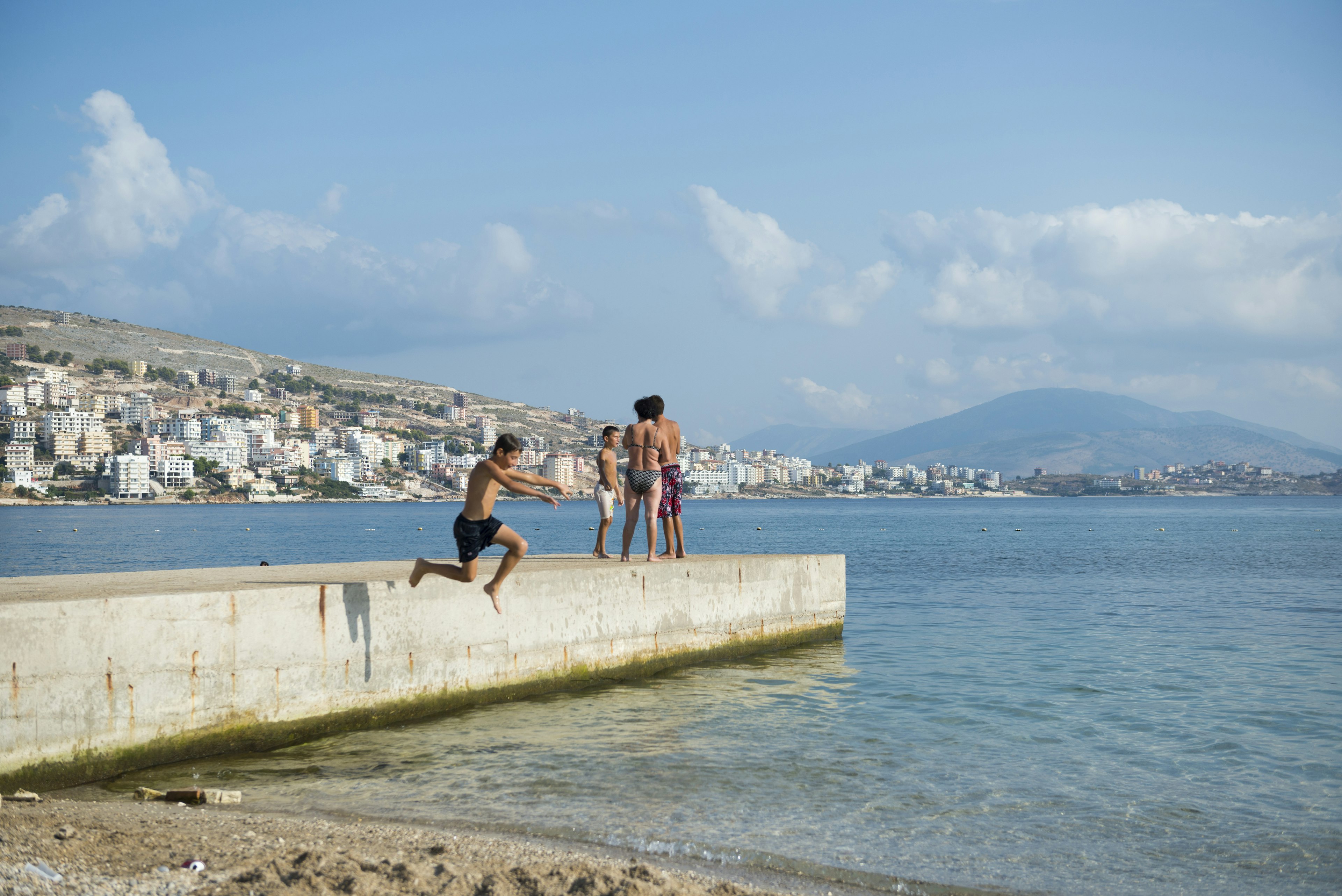 A boy jumps off a pier into the Mediterranean Sea in Sarande (Saranda), Albania