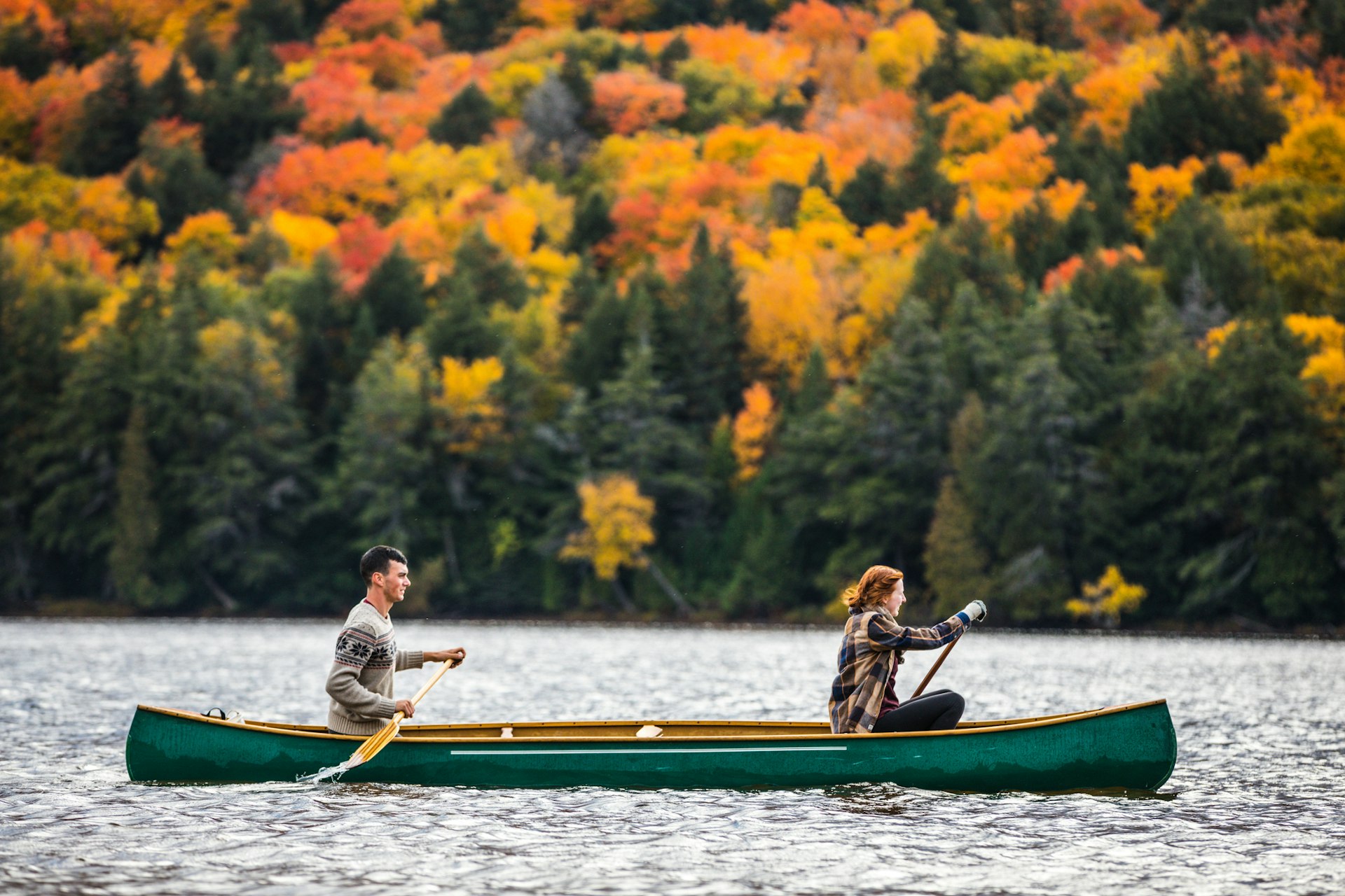 Couple enjoying a canoe ride against a backdrop of fall foliage, Algonquin Park, Ontario, Canada