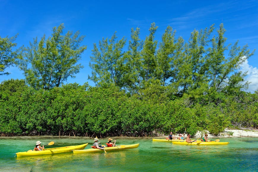 People kayaking in the blue ocean waters lined with mangroves at Lucayan National Park, Bahamas