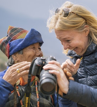 A female tourist has taken a photo of an elderly Bhutanese woman and is now showing the woman that photo on the screen on the back of the camera near Dranjo Goemba - buddhist monastery and school in the uper Paro Valley