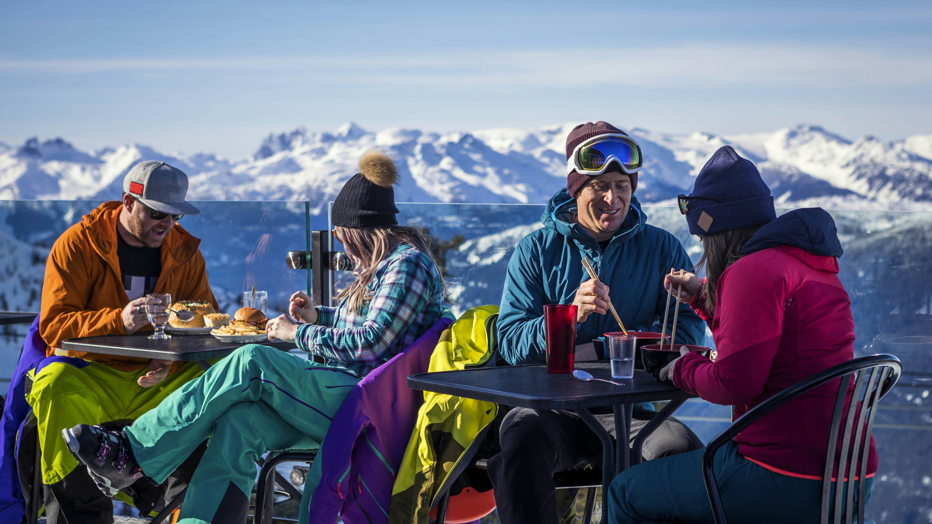 Lyžaři popíjejí nápoje na vrcholu během své lyžařské dovolené v kanadském Whistleru.