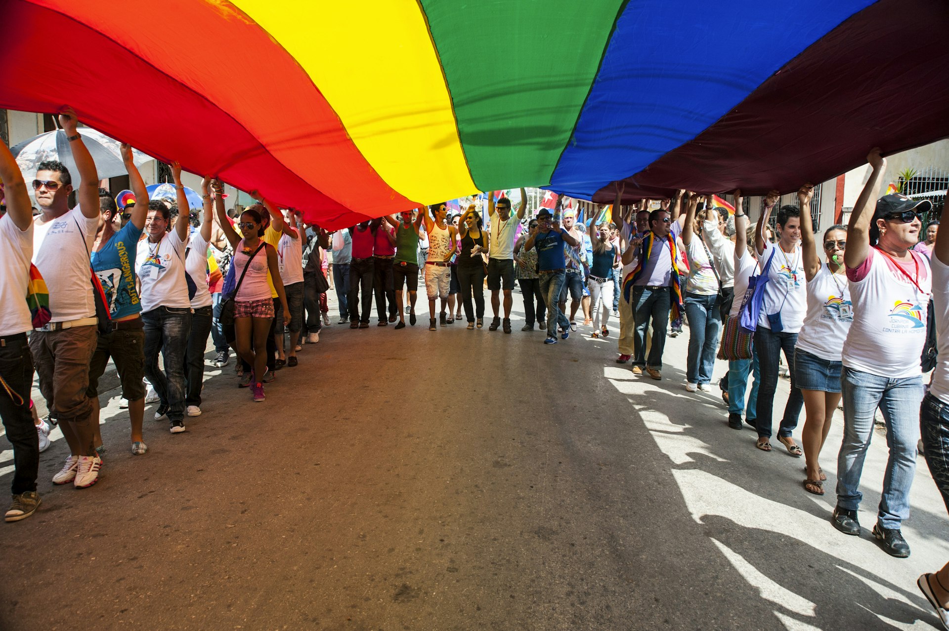 Marchers carry the Gay Pride rainbow-colored flag down a street