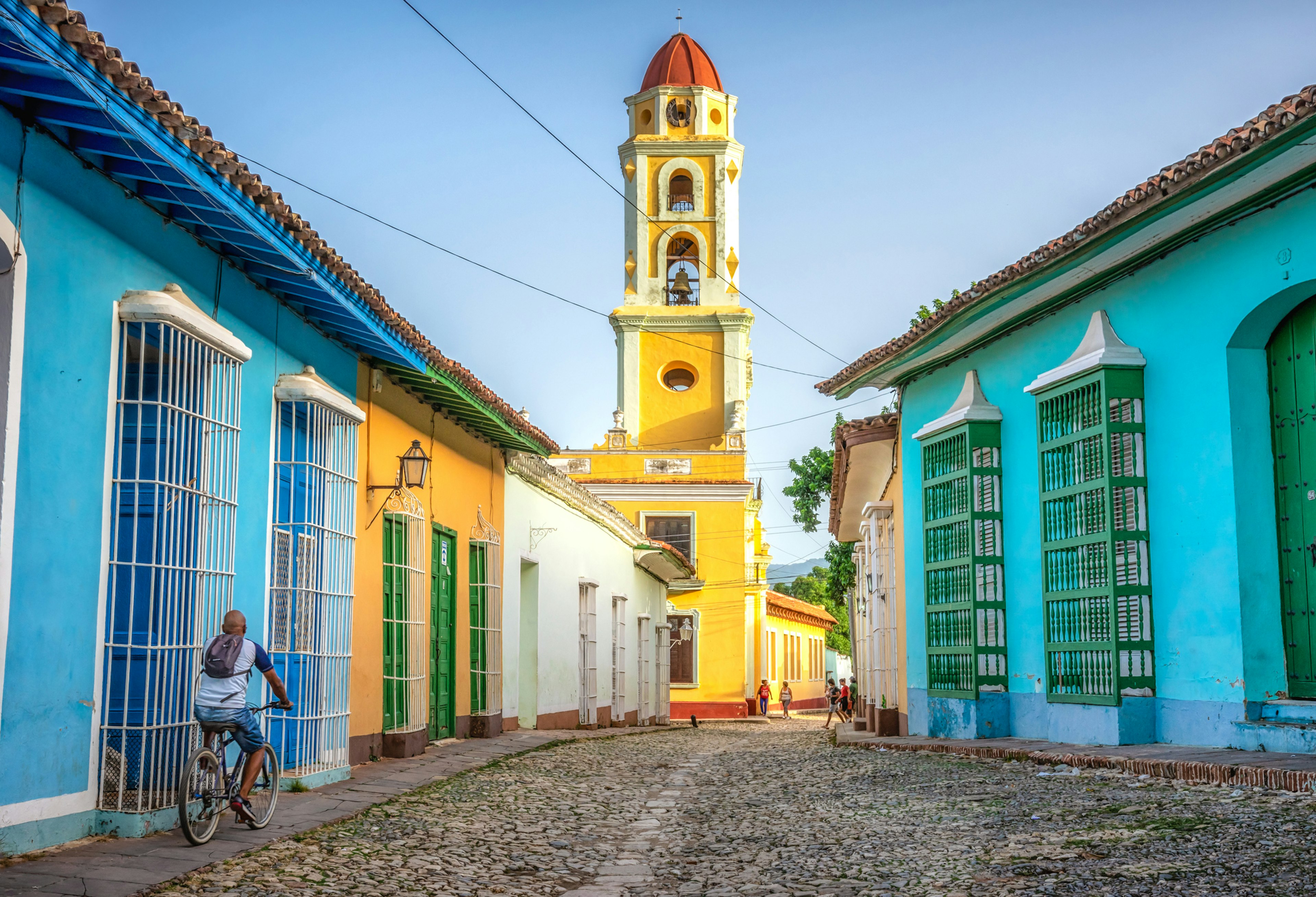 unrecognisable cuban man riding a bike  in the road to San Francisco de Asis church tower in Trinidad, Cuba