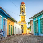 unrecognisable cuban man riding a bike  in the road to San Francisco de Asis church tower in Trinidad, Cuba