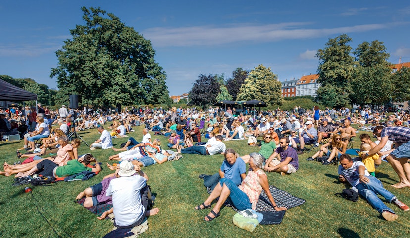 People sitting on the lawns of Kongens Have in Copenhagen during a summer concert
