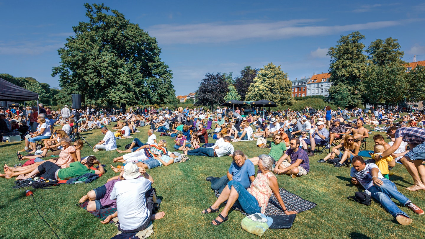 People sitting on the lawns of Kongens Have in Copenhagen during a summer concert