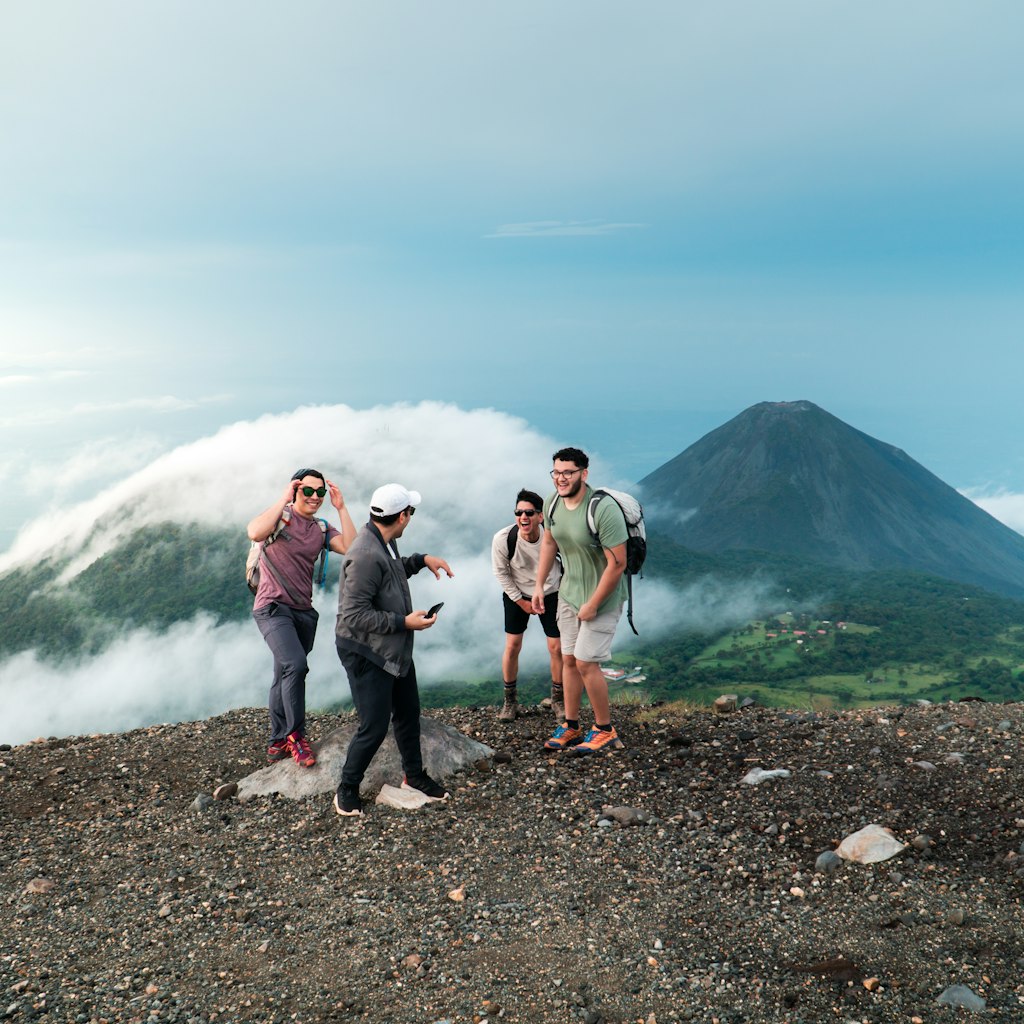 latin tourists have fun on top of a mountain with the El Salvador Volcano at the background