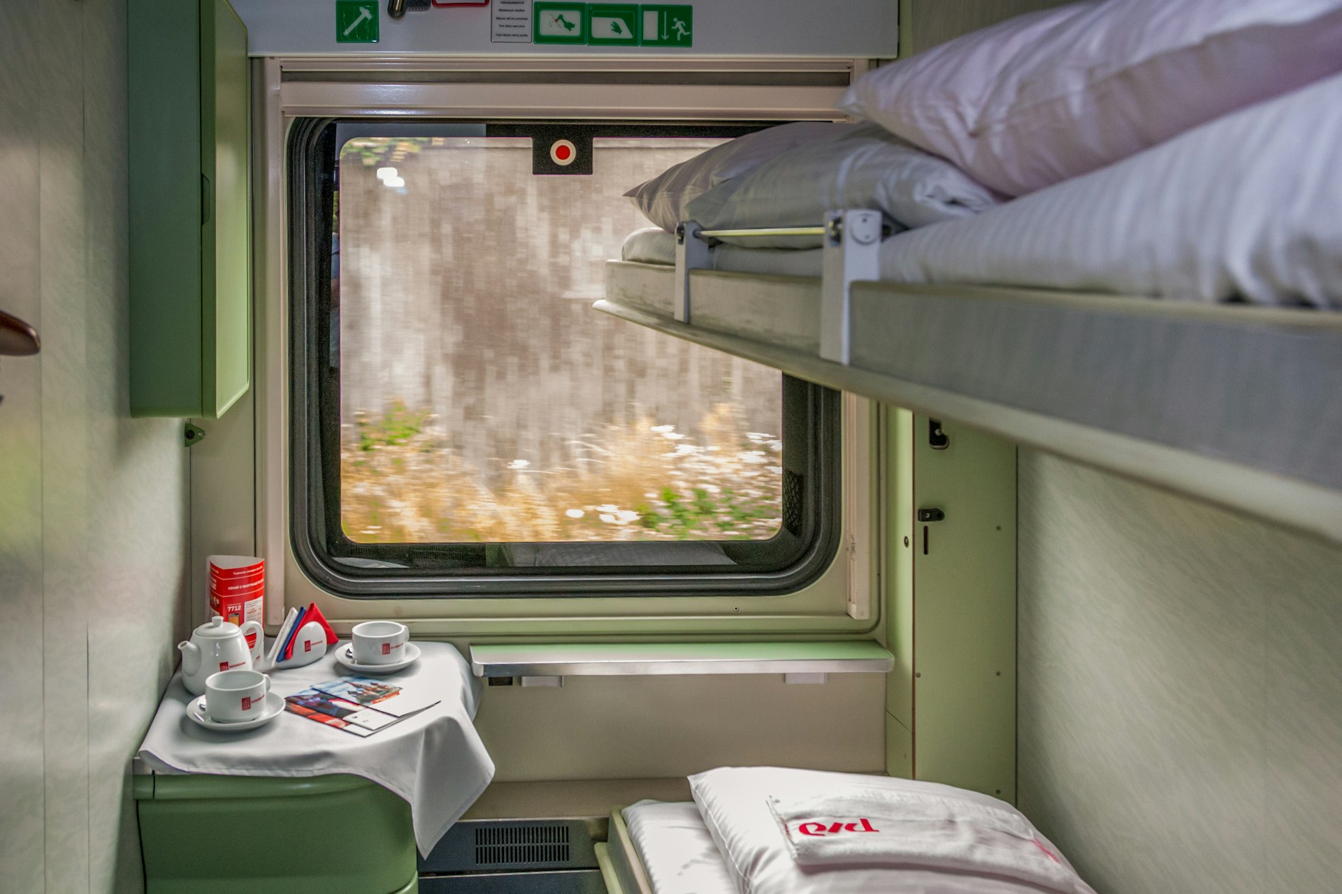 A sleeper train cabin, with two small bunks on the right-hand wall and a window looking out at the passing scenery