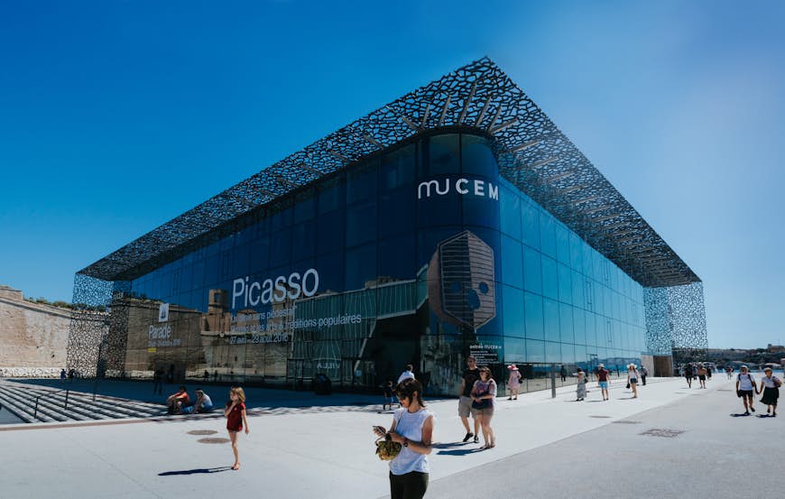 The large glass-and-steel exterior of MuCEM, with people walking by