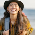 A close-up portait of a happy female solo traveller at the beach.