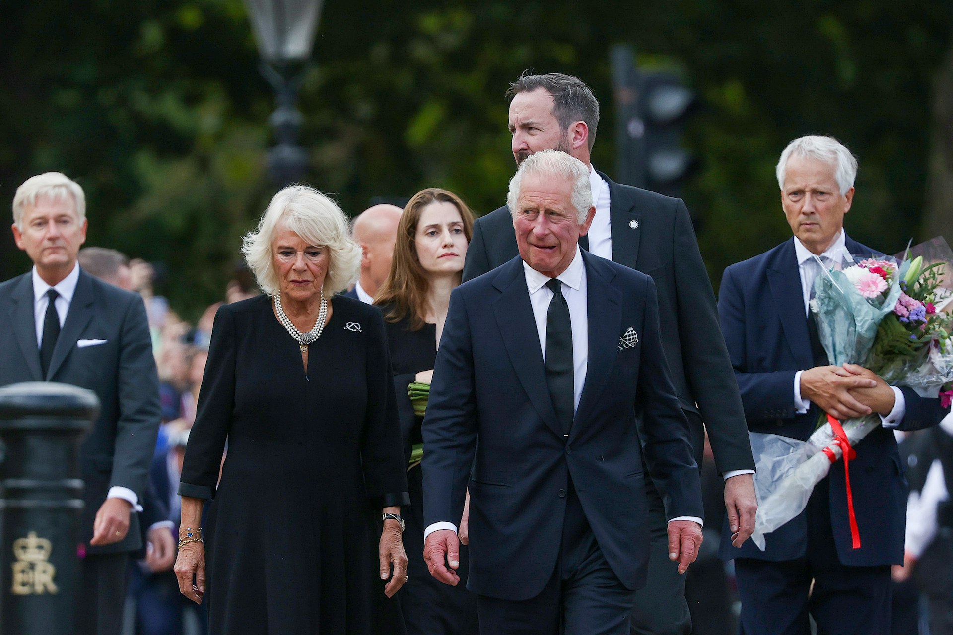 King Charles III, right and Camilla, Queen Consort, look at floral tributes, on the first day of public mourning following the death of Queen Elizabeth II, outside Buckingham Palace in London, UK