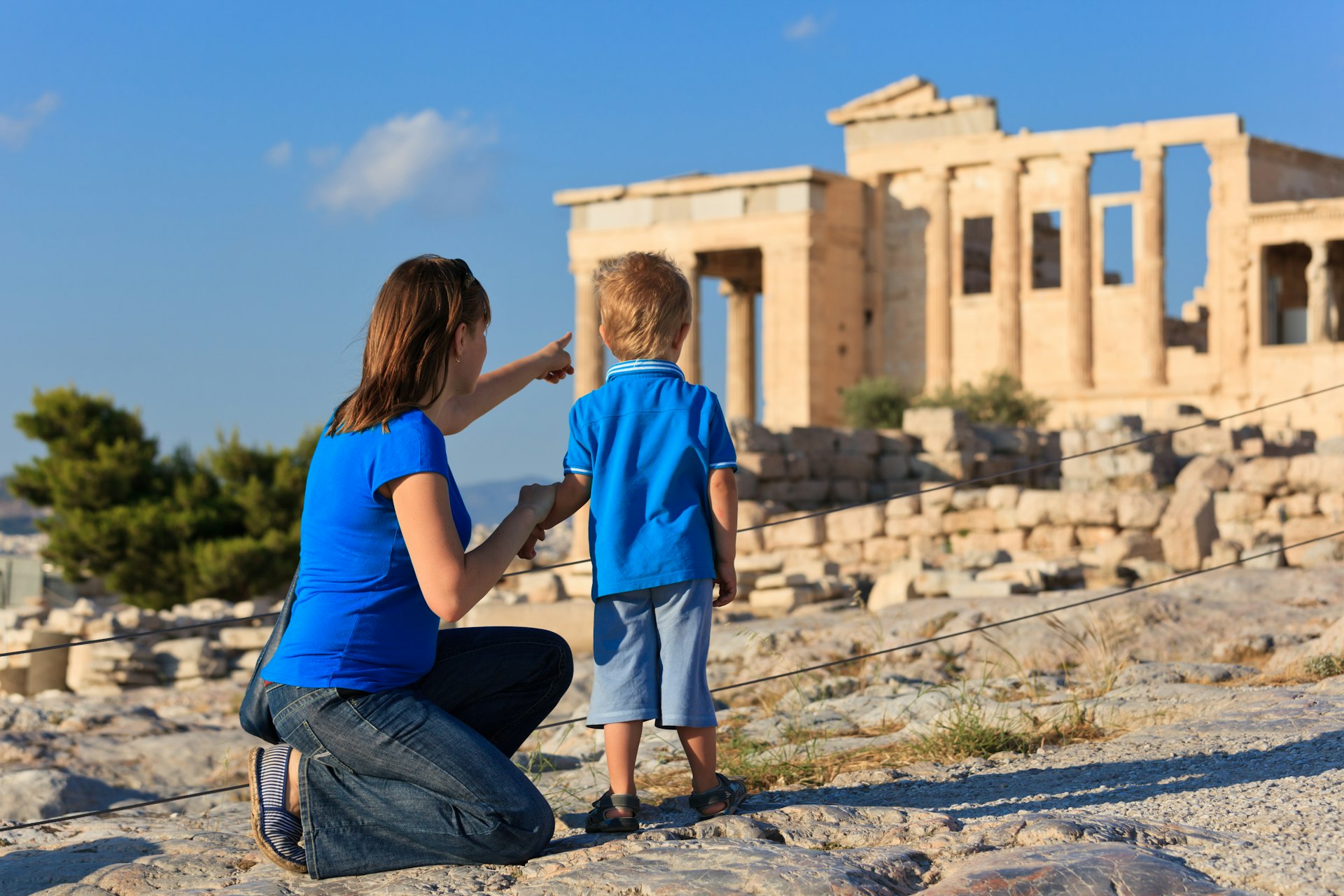A mother showing her young son the acropolis in Athens, Greece, on a sunny day