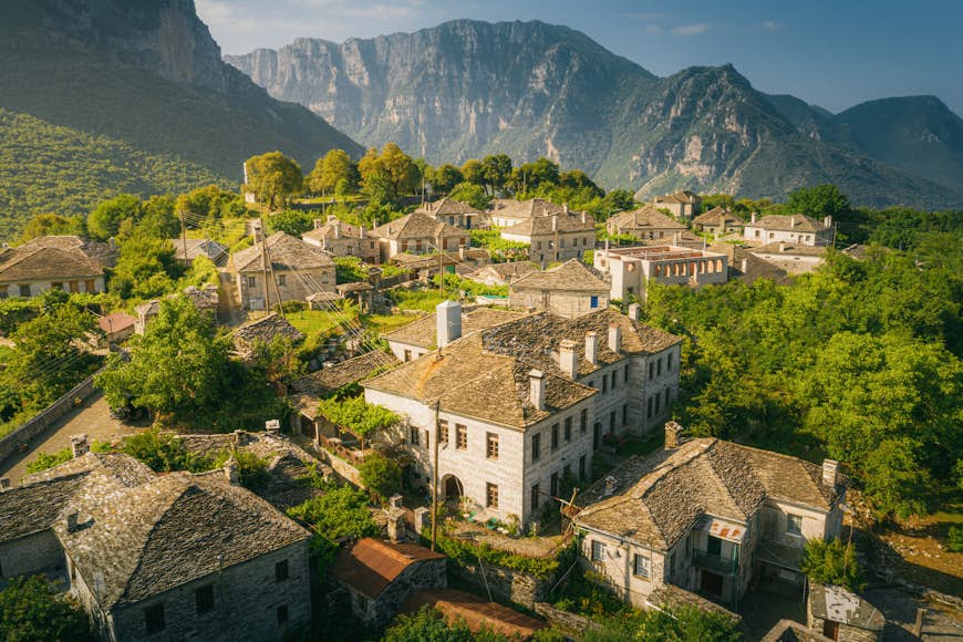 Village de Papingo et Mont Tymfi à Zagori (ou Zagorochoria ou Zagorohoria) dans les montagnes du Pinde, Grèce ;  les bâtiments sont entourés d'arbres et de montagnes