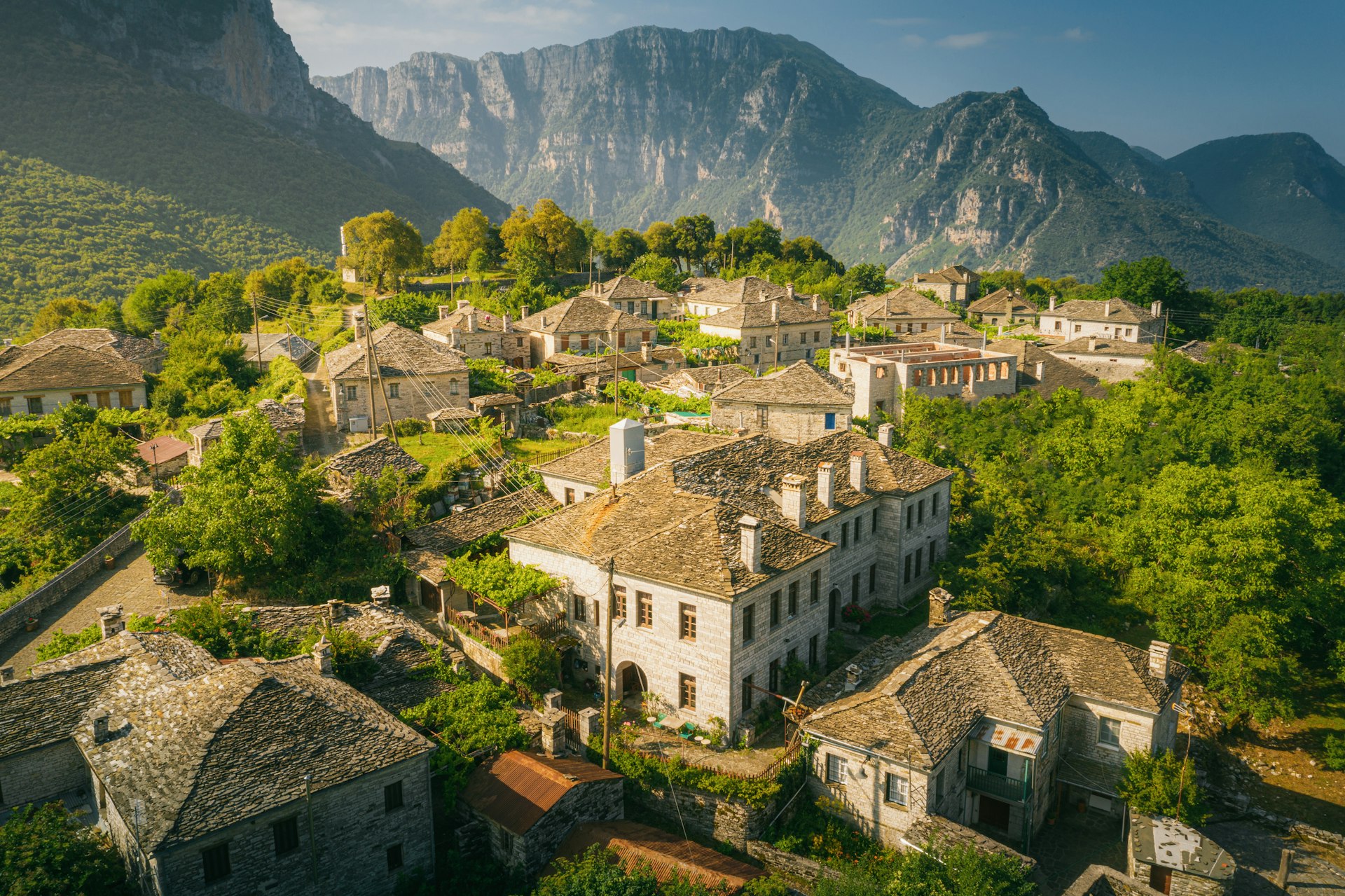 Village of Papingo and Mount Tymfi in Zagori (or Zagorochoria or Zagorohoria)  at Pindus Mountains, Greece; the buildings are surrounded by trees and mountains