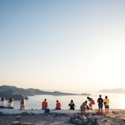 Milos island, Greece - June 12, 2018: Group of tourist sitting on top of the hill in Kastro to watch an amazing sunset. Kastro is the highest spot of Plaka, the capital of Milos.