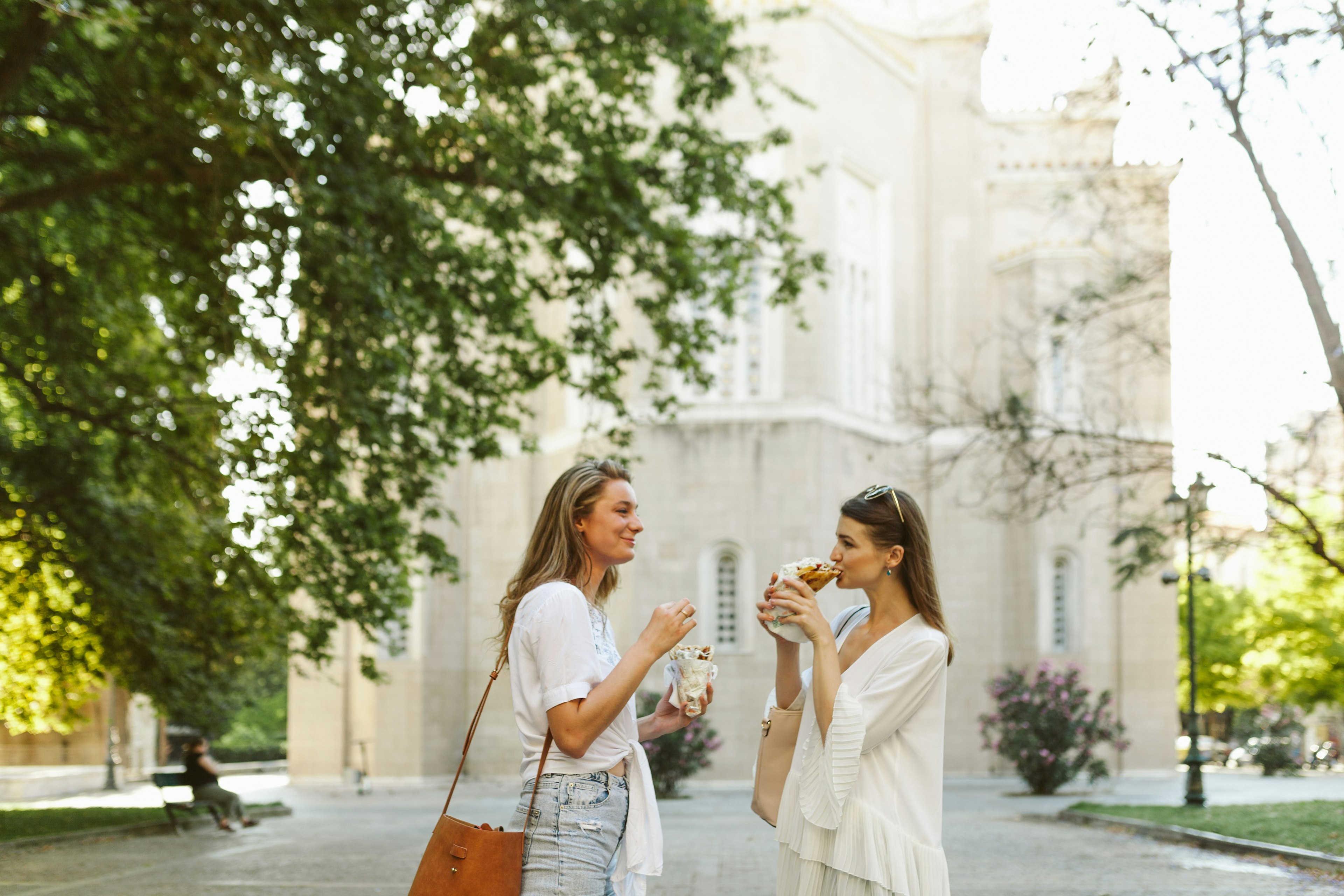 Two female Russian tourists eat Greek souvlaki in Plaka, Athens