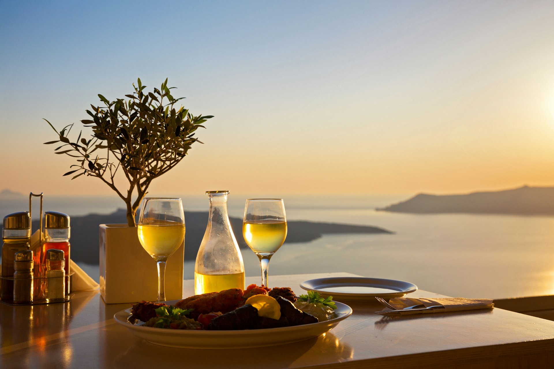 An empty romantic table for two on the island Santorini with the sea in the background and glasses of white wine