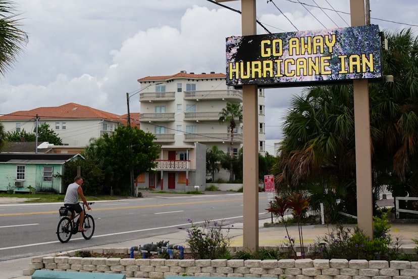 A man rides a bike past the message "Go Away Hurricane Ian" at a condominium complex in St. Pete Beach on September 27, 2022 in St. Petersburg. - The US National Hurricane Center (NHC) said Ian made landfall just southwest of the town of La Coloma, Cuba, at about 4:30 am local time (0830 GMT). The hurricane was packing maximum sustained winds of 125 miles (205 kilometers) per hour, the NHC said, making it a Category 3 storm on the Saffir-Simpson scale. (Photo by Bryan R. Smith / AFP) (Photo by BRYAN R. SMITH/AFP via Getty Images)