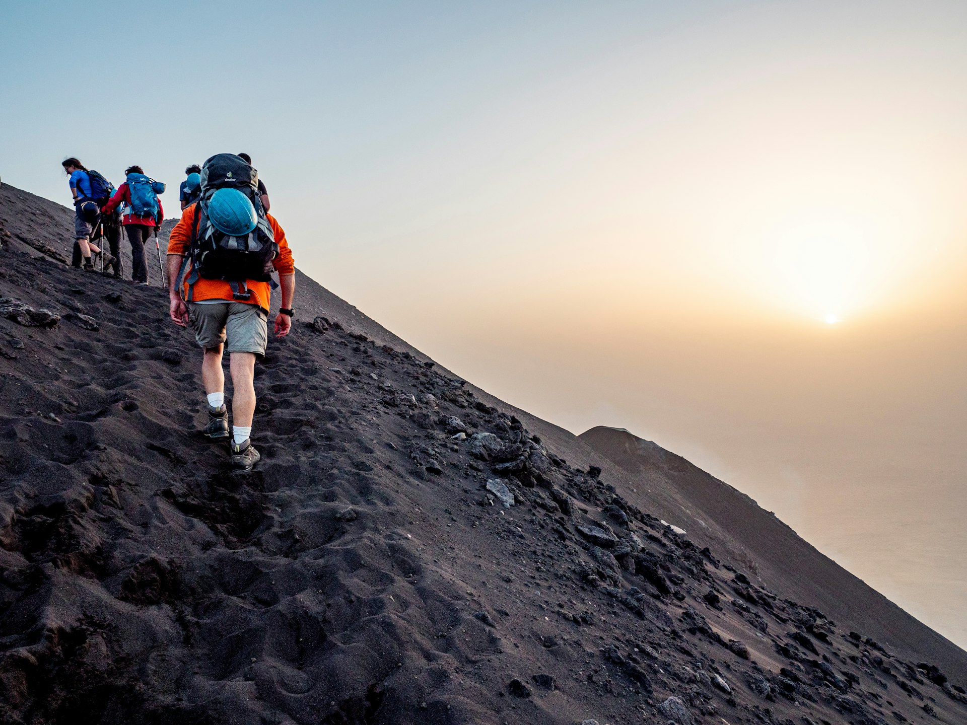 Hikers walking on gray ash at sunset on Stromboli volcano on Sicily, Italy