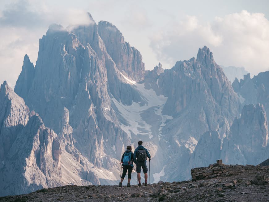 Couple of hikers standing and admiring stunning beauty of impressive jagged peaks of Cadini di misurina mountain group in Dolomites, Italy