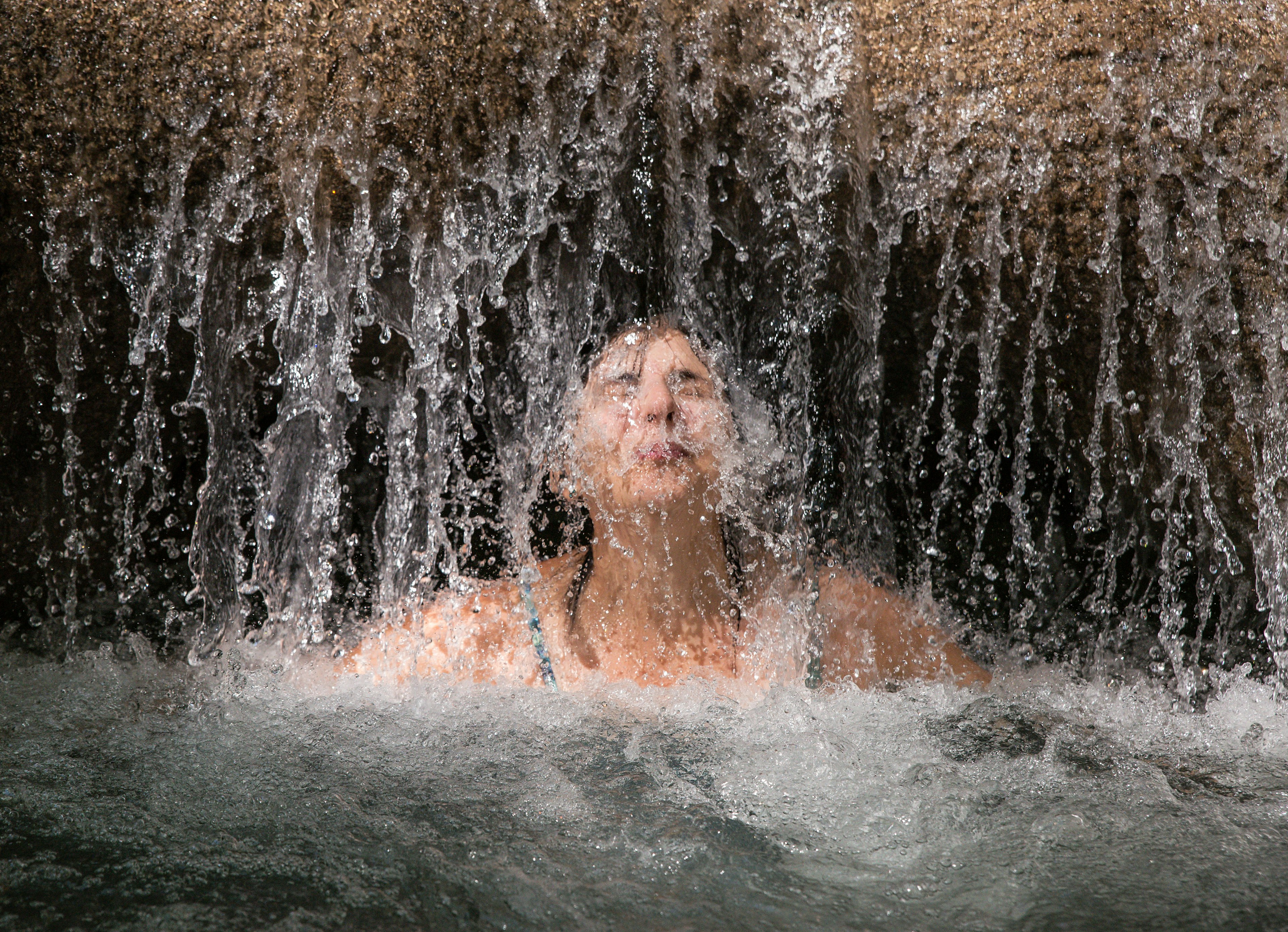 Woman enjoys a refreshing water massage at Mayfield Falls, Glenbrook, Jamaica