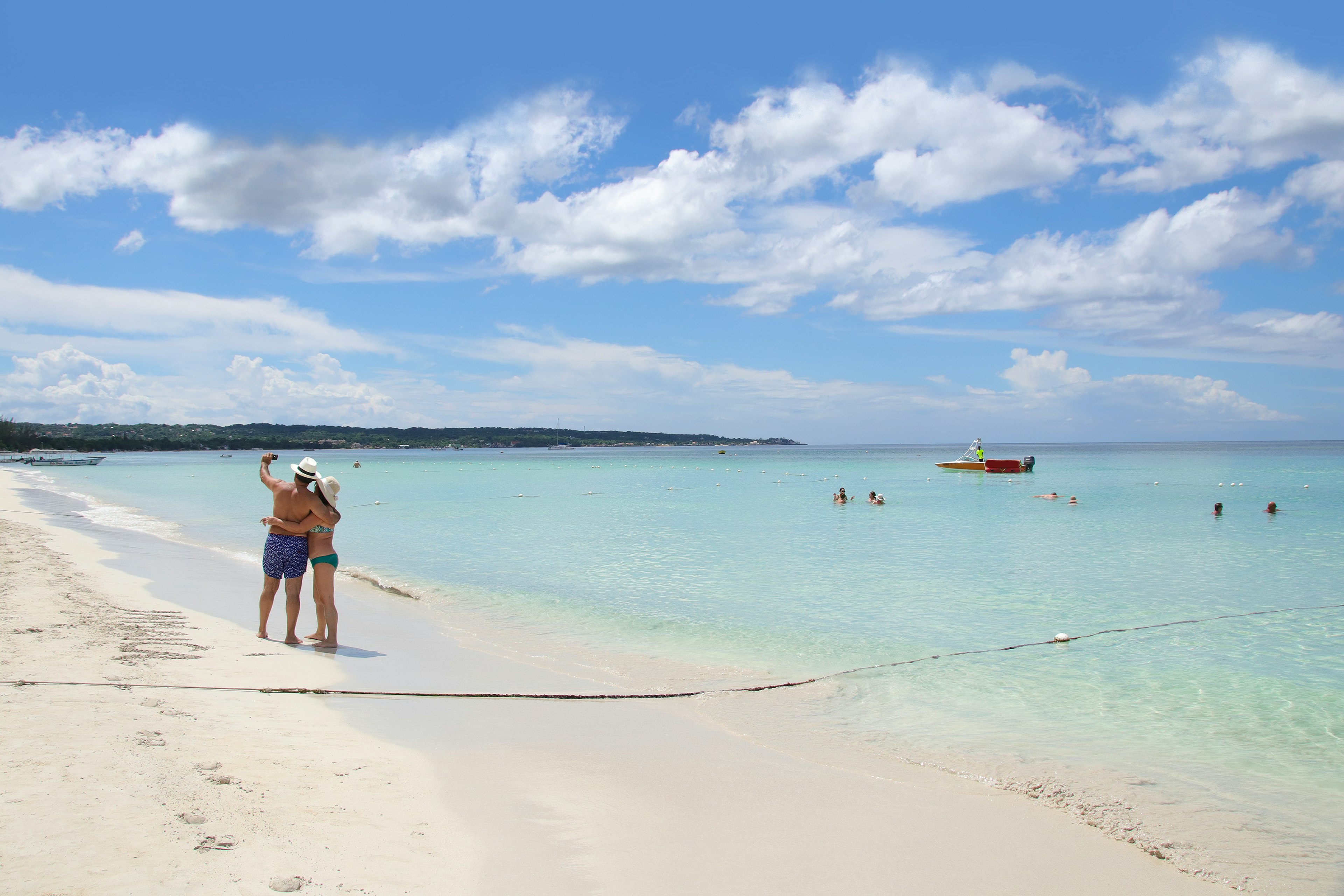 Distant view of two people taking a selfie on Negril Beach