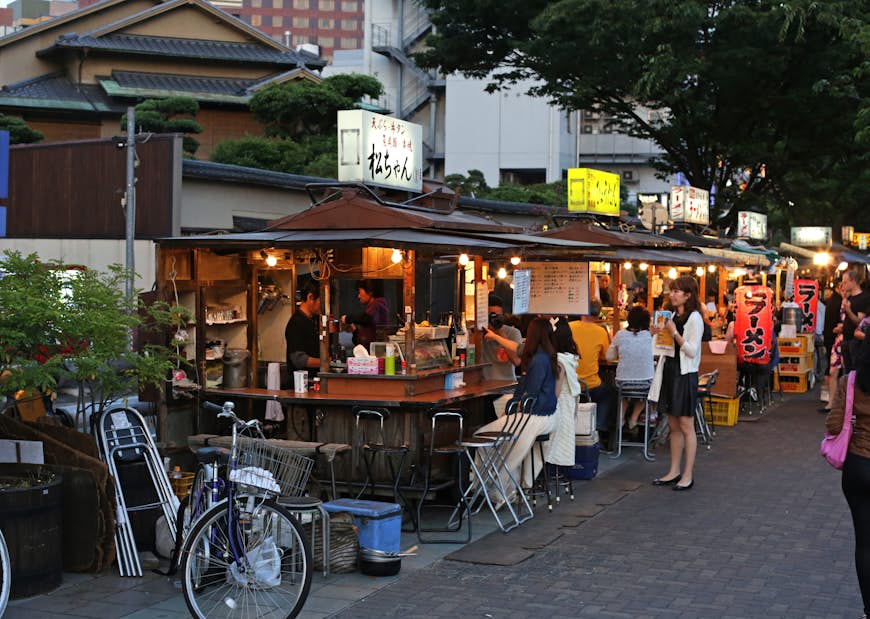 Customers enjoy their meals at a series of street food stalls lining the street in Fukuoka, Japan