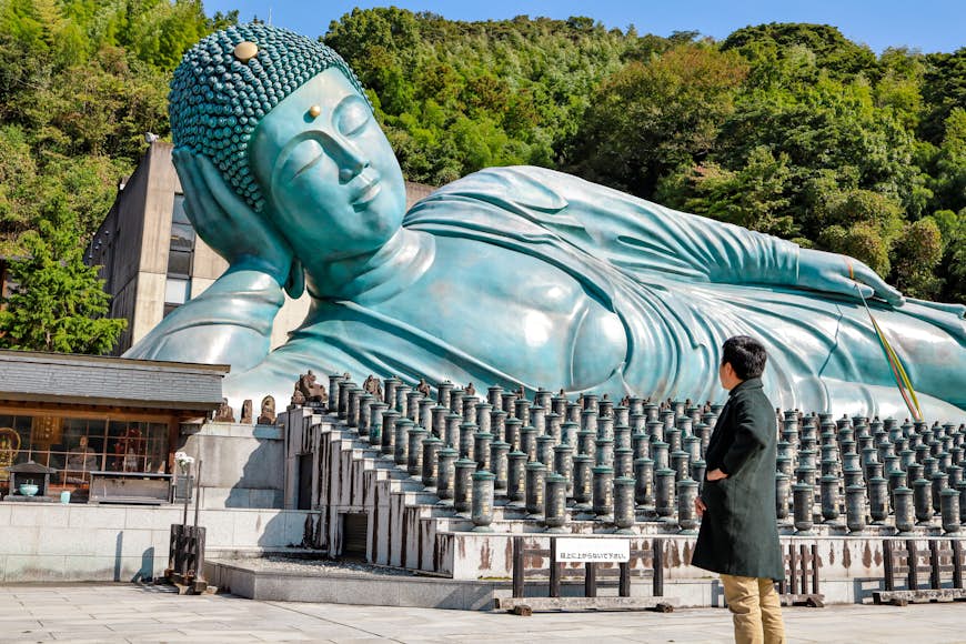 A large bronze reclining Buddha in a park