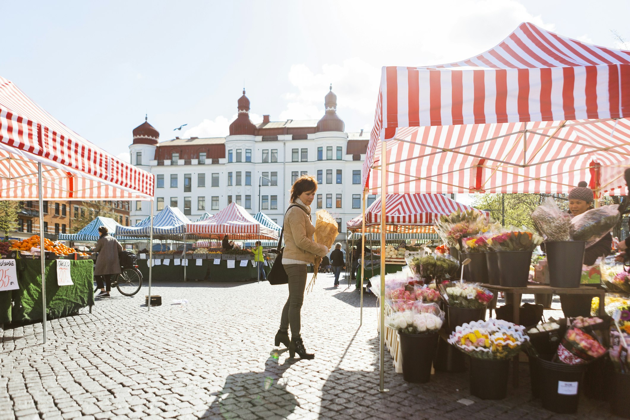 Full length side view of woman buying flowers at market stall in Malmo, Sweden