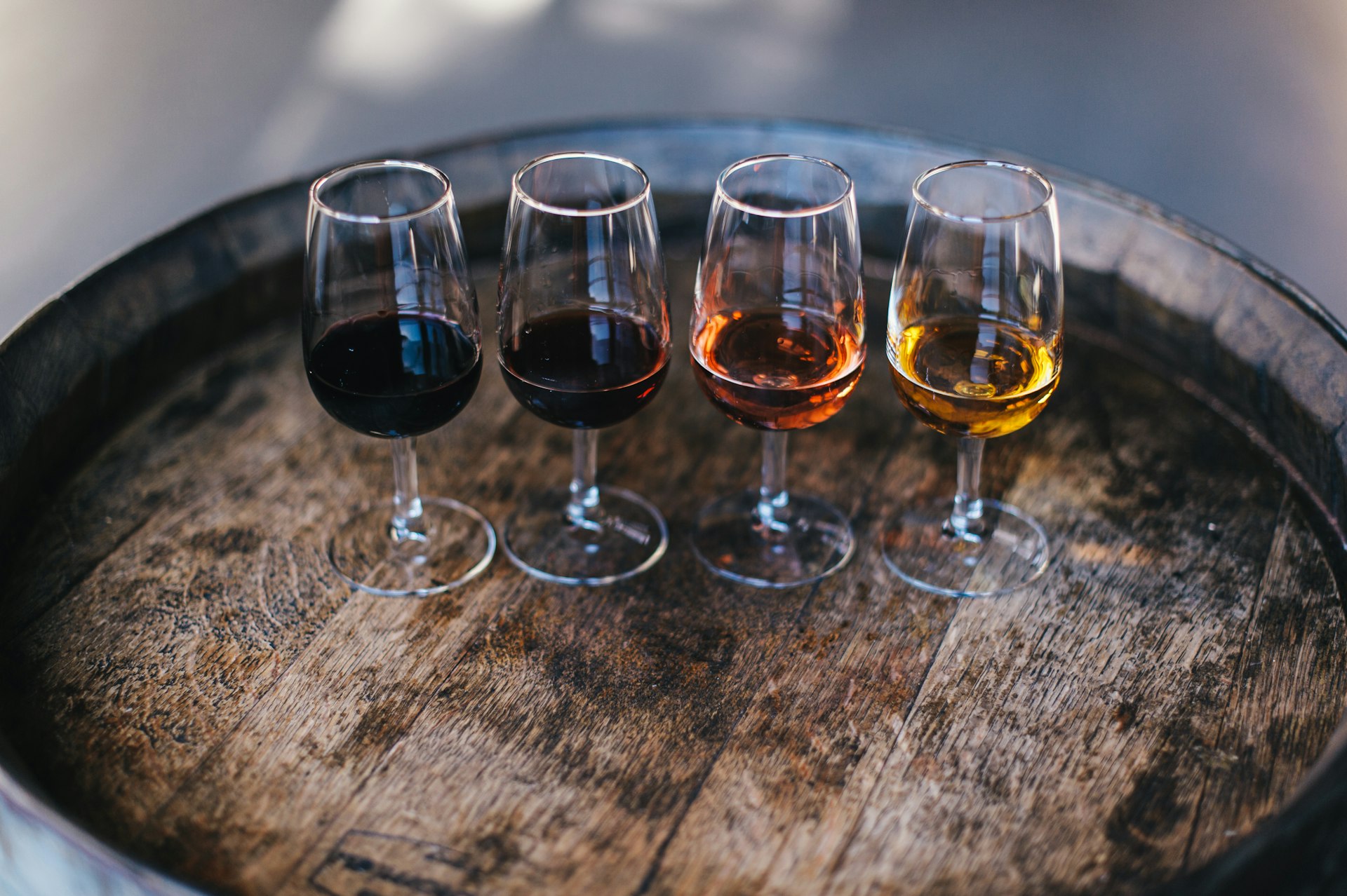 Four different types of port produced in Porto, Portugal, in glasses on a wooden barrel