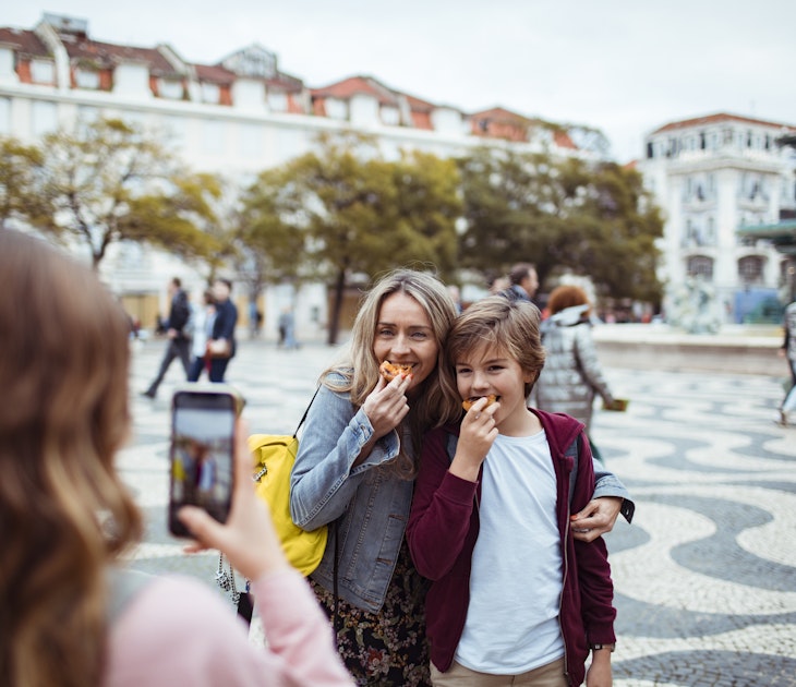 Close up of a young family taking pictures together while exploring the Rossio square in Lisbon and having Portuguese tarts