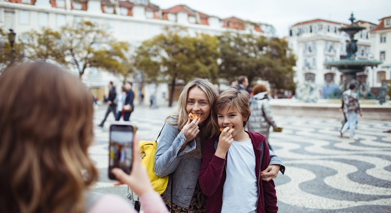 Close up of a young family taking pictures together while exploring the Rossio square in Lisbon and having Portuguese tarts