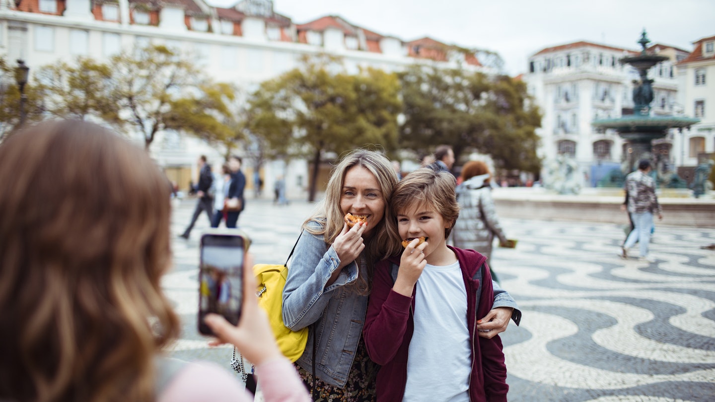 Close up of a young family taking pictures together while exploring the Rossio square in Lisbon and having Portuguese tarts