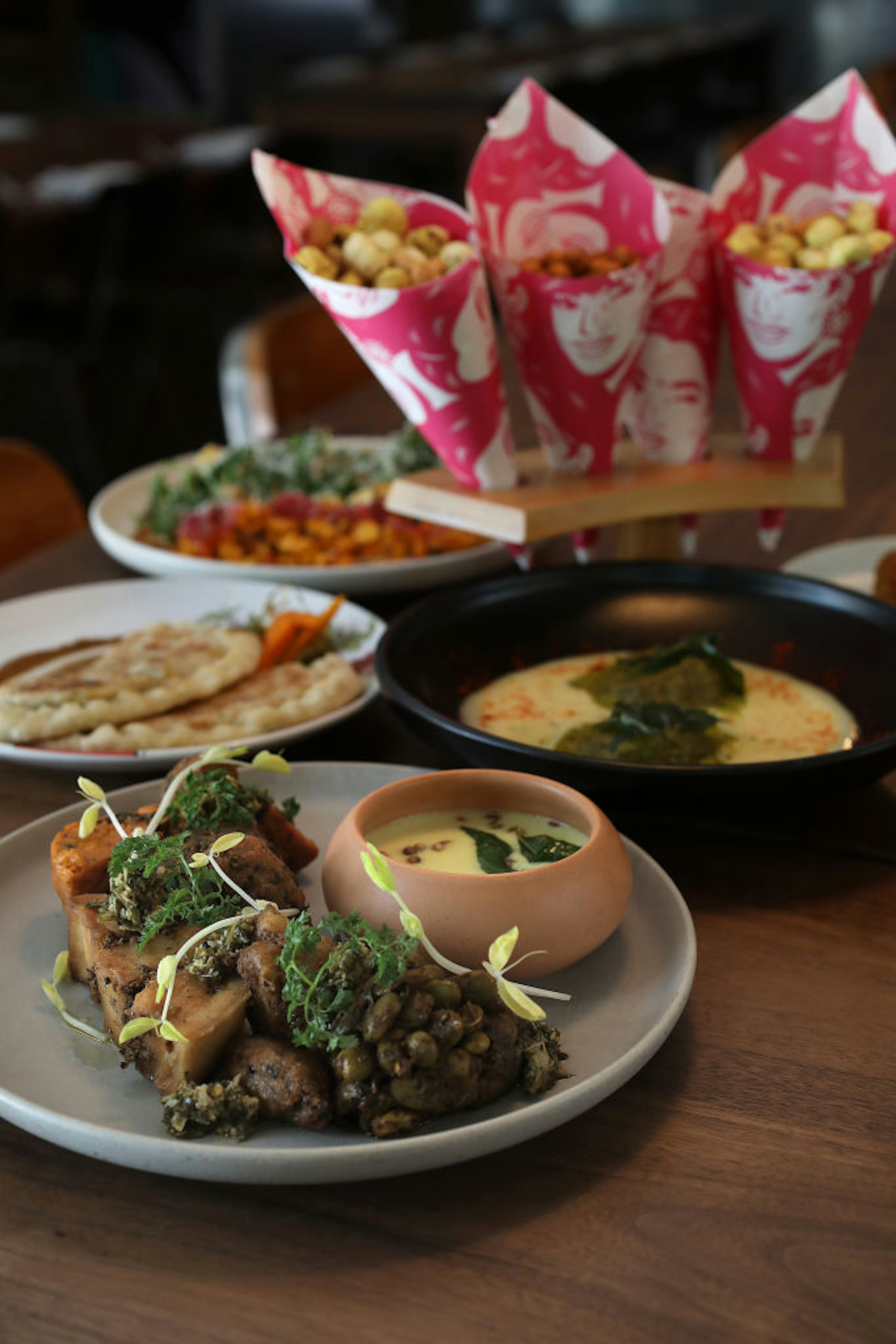 Cones of channa and other dishes sit on the table in a restaurant.