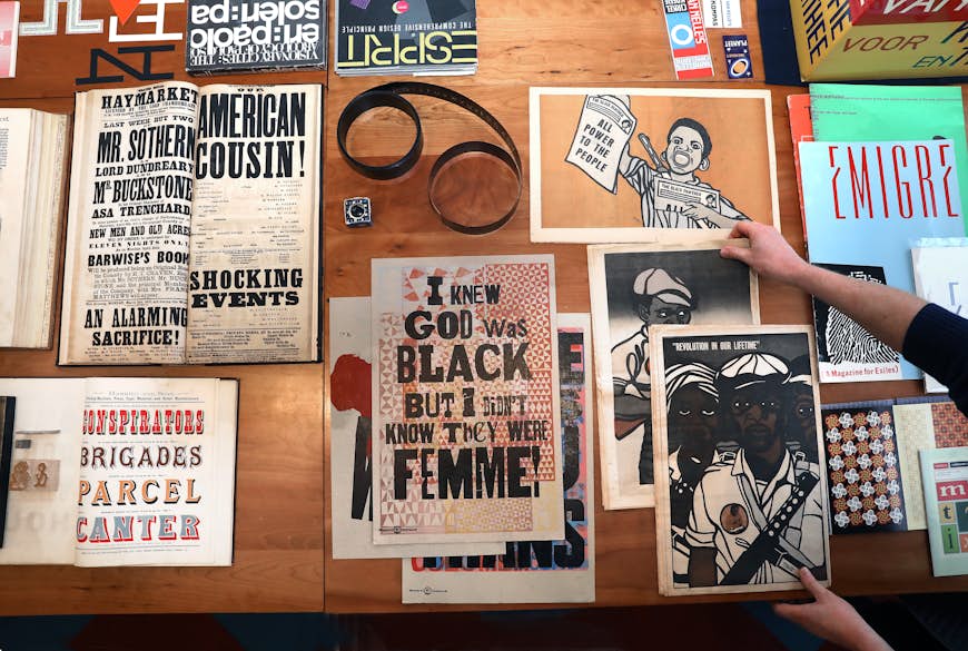 Protest posters from history lay flat on a table. 