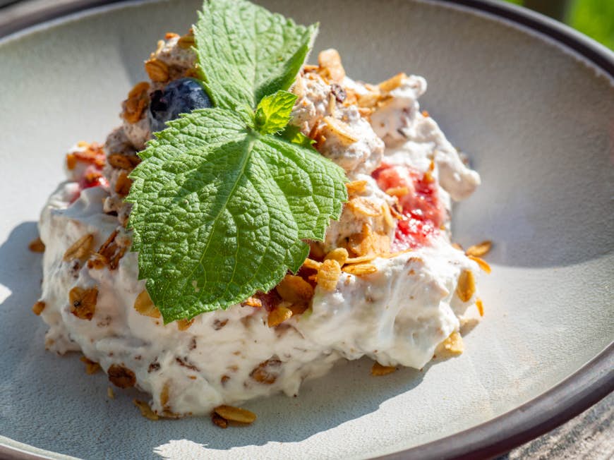 Cranachan, traditional Scottish dessert with whipped cream, whisky, honey, strawberries, blueberry and oatmeal, decorated with green mint leaf 