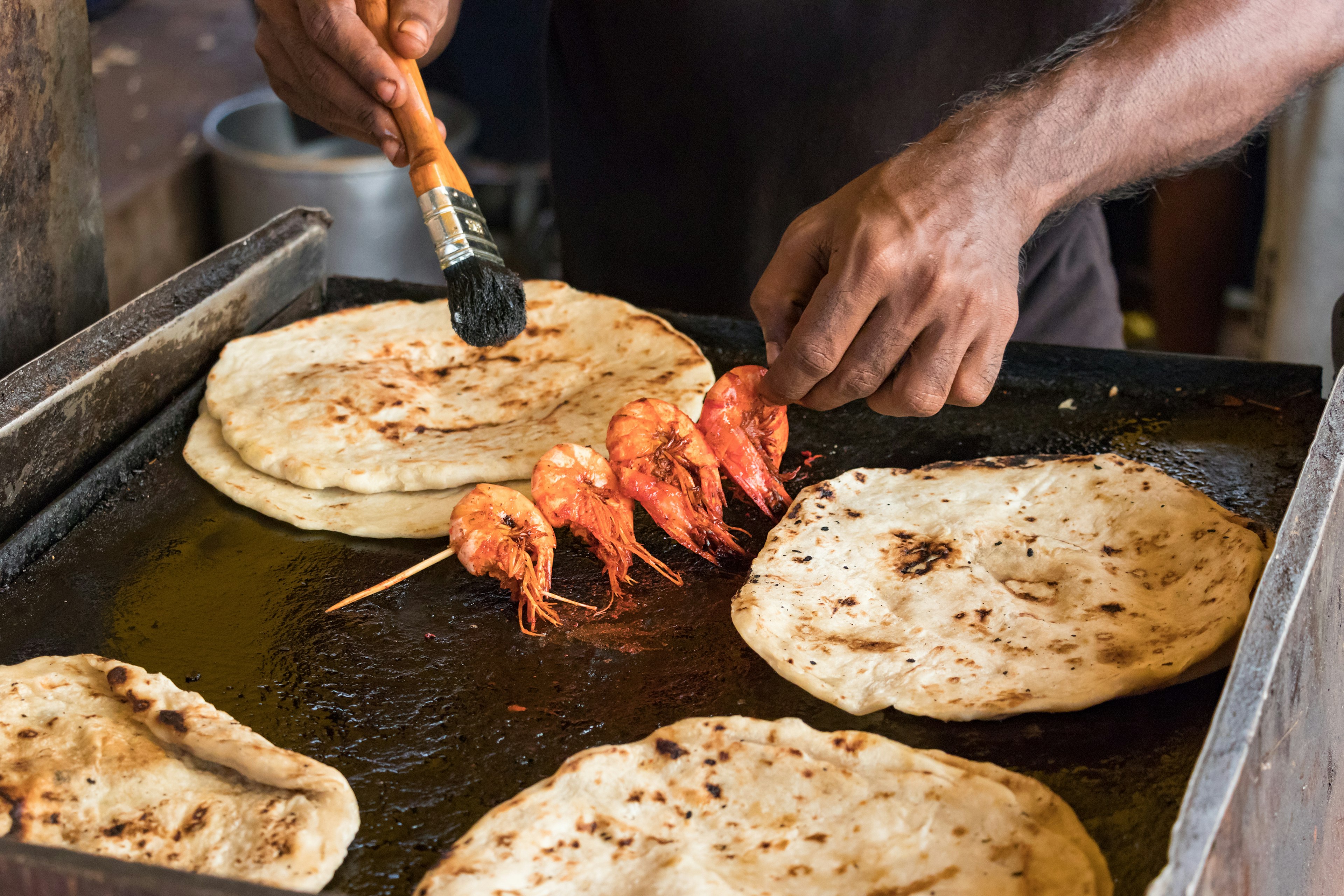 A Sri Lankan cook making prawns with pol roti flat bread in Colombo